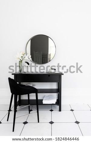 Vertical photo of modern interior design in contemporary apartment with chair near makeup table in bathroom, towels, natural cosmetics for morning beauty procedure and daily routine at home