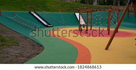 Children's playground, with a rubber multi-colored coating, slides and nets for games are visible. Royalty-Free Stock Photo #1824868613