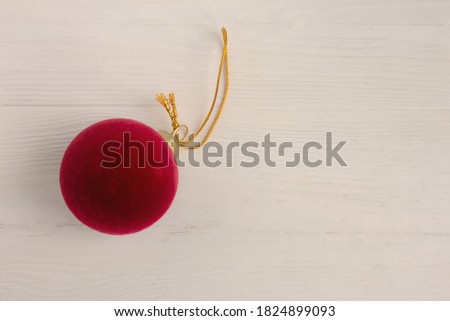 Red velvet ball with a gold loop for a Christmas tree on a white background with space for text. Poster, postcard. Royalty-Free Stock Photo #1824899093