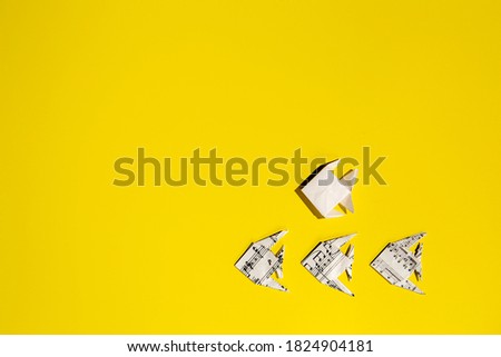 School of origami fishes on background of yellow. Sheet music paper origami animals.