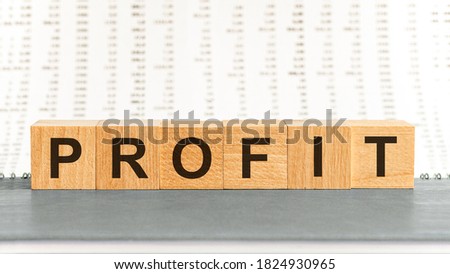 PROFIT word made with building blocks. PROFIT on wooden cubes on grey notepad. Business concept.