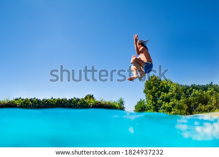 Profile photo of the boy jump high in action happy pose with lifted hands dive in the outdoor swimming pool