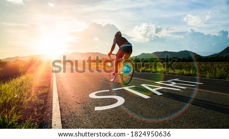 Concept of start straight and beginning for cooperation.Blurry Man ride on bike and word start written on the road at sunset add lens flare.Concept of challenge or career path,business strategy. Royalty-Free Stock Photo #1824950636
