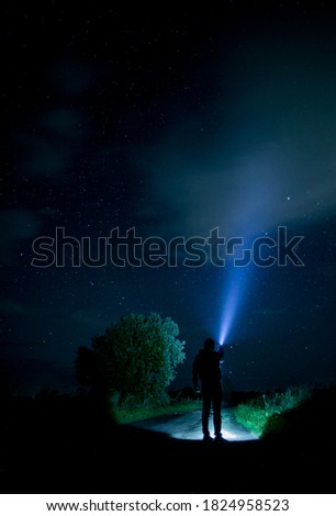man at night with a flashlight under the starry sky