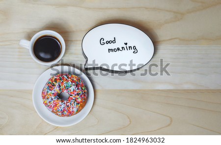 Cup of coffee with a donut and a plate on a wood texture background. Concept on the topic Good Morning.