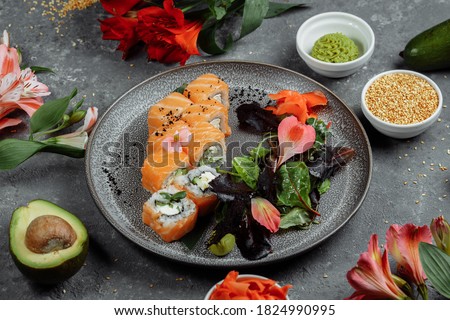 Delicious fresh sushi rolls with salmon and philadelphia cheese on gray plate on dark stone background. Traditional japanese seafood, healthy food concept.