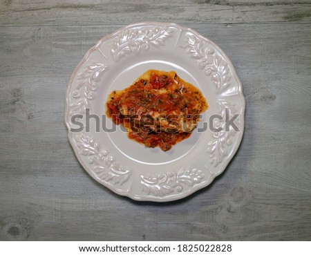 Top view of a portion of chicken cacciatore on a plate. Baked chicken with tomato basil sauce.