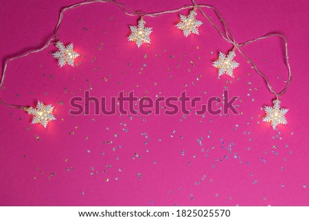 Stars garland on pink background with glittered little stars. Christmas theme with space for text writing, greeting. Concept banner for Christmas card, advertising. Top view.