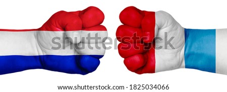 The concept of the struggle of peoples. Two hands are clenched into fists and are located opposite each other. Hands painted in the colors of the flags of the countries. France vs Luxembourg