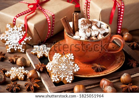 Ceramic  mug filled with hot chocolate and marshmallows, gingerbread cookies and gift boxes on wooden background, Christmas holidays