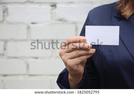 Business card closeup - businesswoman in dark blue suit holding blank empty card. Business startup concept.