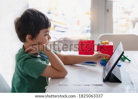 Kid stay at home watching cartoon on tablet, Child using digital tablet searching information on internet for his homework during covid-19 lock down,Social Distancing, learning online education
