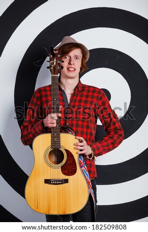 A musician. Portrait of emotional young handsome guy with a guitar in studio.