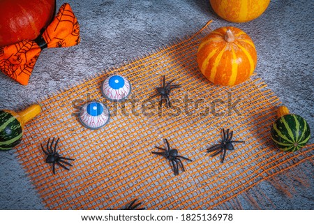 Halloween holiday, carnival background, scary eyes, pumpkin and haunted spiders on an orange grid.

