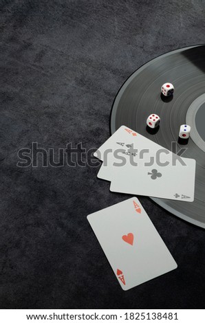 Vinyl record, dice, playing card on the dark grey table.Concept of casino atmosphere.Empty space