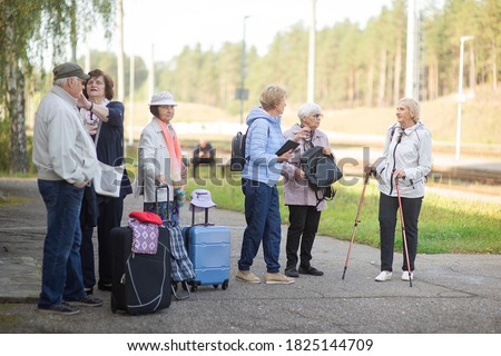 A group of positive senior elderly people travelers waiting for train before going on a trip