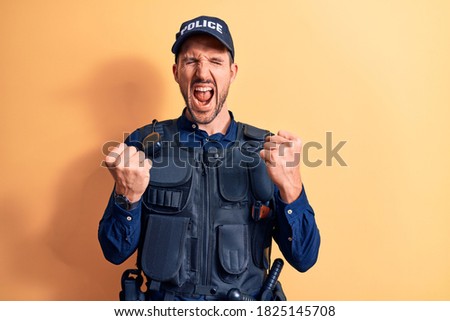 Young handsome policeman wearing police uniform and bulletprof over yellow background celebrating surprised and amazed for success with arms raised and eyes closed