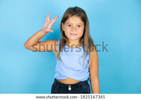 Young beautiful child girl over isolated blue background doing hand symbol