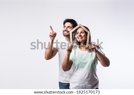 Indian young family couple and real estate concept - buying or rental, standing against white background Royalty-Free Stock Photo #1825170173