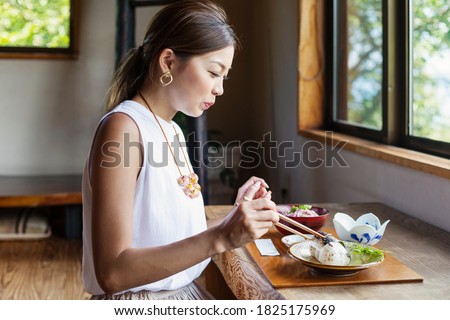 Japanese woman sitting at a table in a Japanese restaurant, eating. Royalty-Free Stock Photo #1825175969