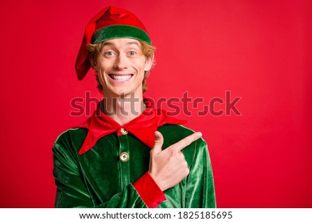 Photo of positive elf guy point finger empty space x-mas christmas ads wear costume cap isolated on bright red color background