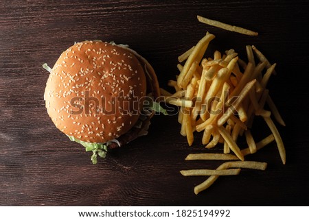 close-up of a hamburger and a pile of French fries on a wooden background