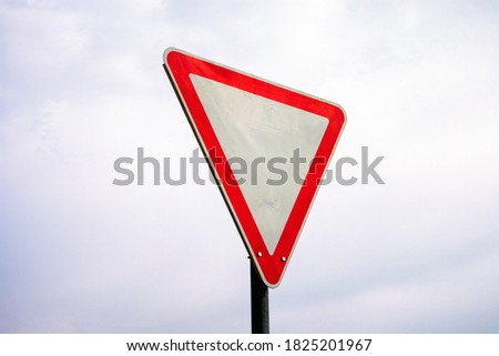 A modern yield sign against cloudy sky