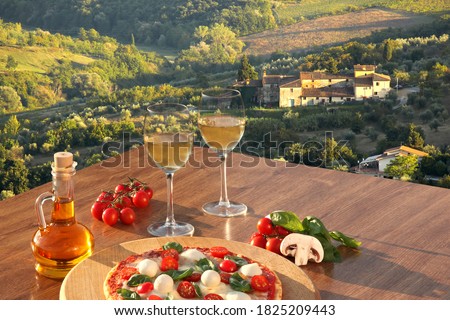 Italian pizza with glasses of white wine against Tuscan vineyards near the Florence in Italy Royalty-Free Stock Photo #1825209443