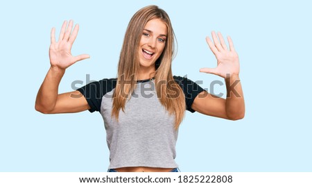 Young blonde woman wearing casual clothes showing and pointing up with fingers number ten while smiling confident and happy. 