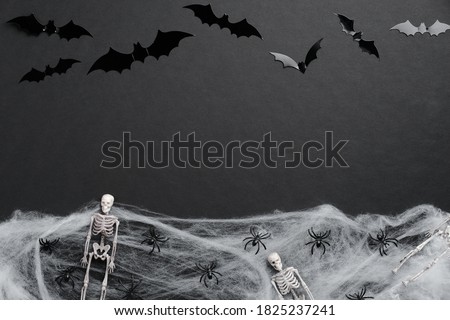 Happy Halloween card. Flat lay composition with silhouette of bats, skeletons, spiders, spiderweb on black background.