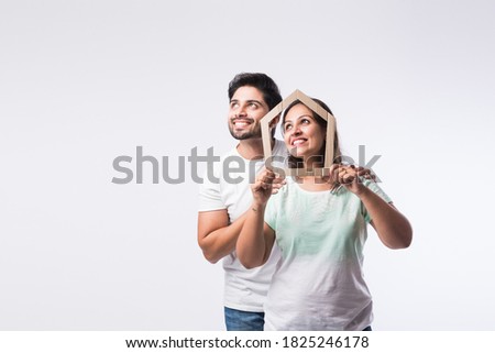 Indian young family couple and real estate concept - buying or rental, standing against white background Royalty-Free Stock Photo #1825246178