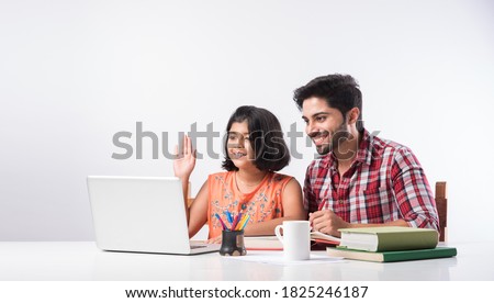 Cute Indian girl with father studying or doing homework at home using laptop and books - online schooling concept Royalty-Free Stock Photo #1825246187
