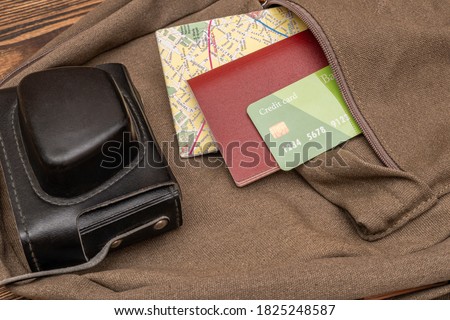 Tourist map, photo camera, credit card, passport in the pocket of the travel backpack