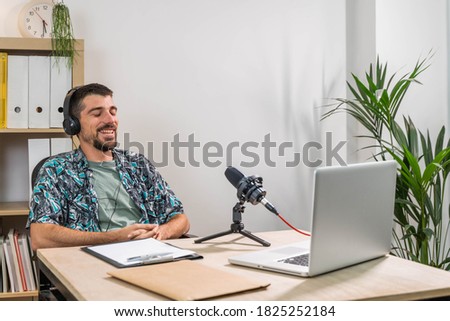 Man working as radio host at radio station sitting in front of microphone. Young radio host moderating a live show for radio. 
Working at home. 