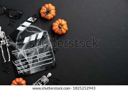 Movie clapperboard and halloween decoration on black table. Horror movie night, halloween party invitation. Halloween background
