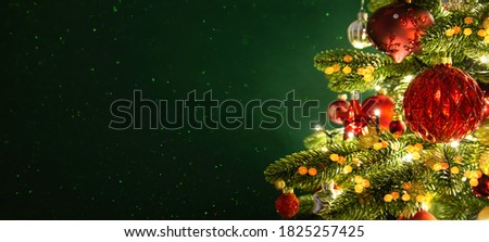 Decorated with ornaments and lights Christmas tree on dark green background. Merry Christmas and Happy Holidays greeting card, frame, banner. New Year. Noel. Winter holiday theme. 