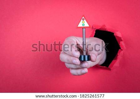 Traffic Light concept. Road sign in a woman's hand. Red background. Copy space
