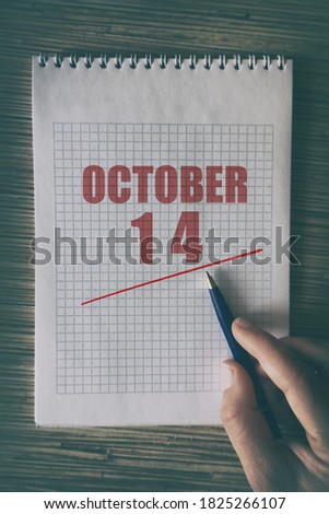 october 14th. Day 14 of month,  Close up of human hand with pen on notepad with red underlined date.  autumn month, day of the year concept.