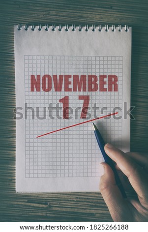 november 17th. Day 17 of month,  Close up of human hand with pen on notepad with red underlined date.  autumn month, day of the year concept.