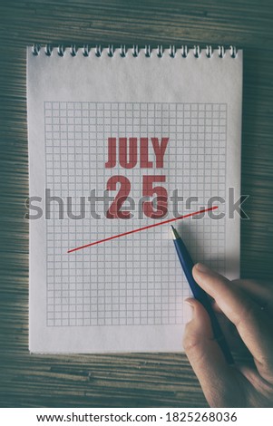 july 25th. Day 25 of month,  Close up of human hand with pen on notepad with red underlined date.  summer month, day of the year concept.