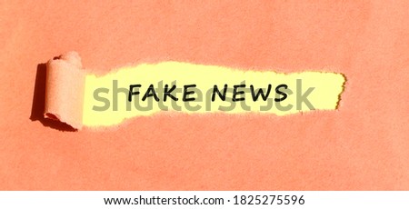The text appearing on yellow paper behind torn color paper. Top view.