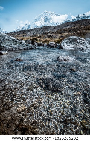 Landscape with a clear mountain river with clear water on the background of a snowy mountain in the Himalayas. Vertical picture