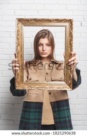 Young woman holds the frame in front of her. Boundary and stereotype concept