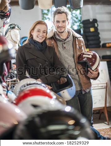 handsome couple choosing a trendy motorcycle's helmet in a specialized shop