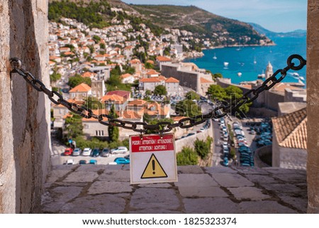 Dubrovnik, Croatia - 09/22/2019 Attention Danger warning sign overlooking a beautiful view 