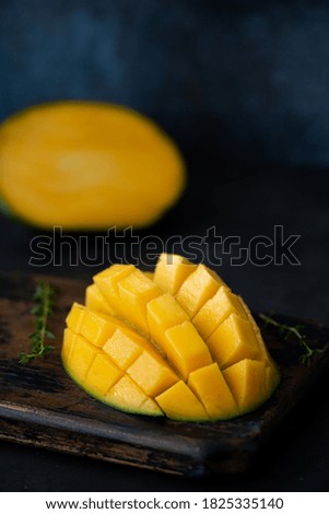 large ripe mango cut into pieces on a dark blue background