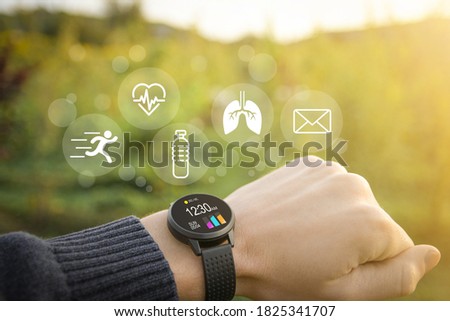 Smart watch, fitness tracker on hand in the outdoor on a blurred green background with icons of basic functions.Concept of The technology to check health. Close up