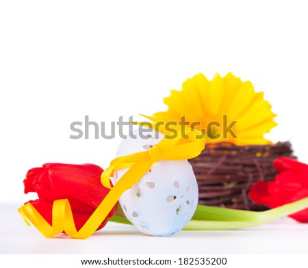Easter eggs with gerbera, daisies isolated on white background. Easter concept with yellow gerbera, one egg and red tulip on white table.