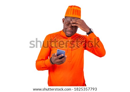 a handsome businessman in orange outfit standing over white background looking at cellphone, hand on forehead looking stressed