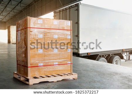Cargo Trailer Truck Parked Loading at Dock Warehouse. Freight Truck. Shipment. Delivery Service. Package Boxes on Pallet Waiting to Load into Container Truck. Supply Chain. Logistics Transportation. Royalty-Free Stock Photo #1825372217